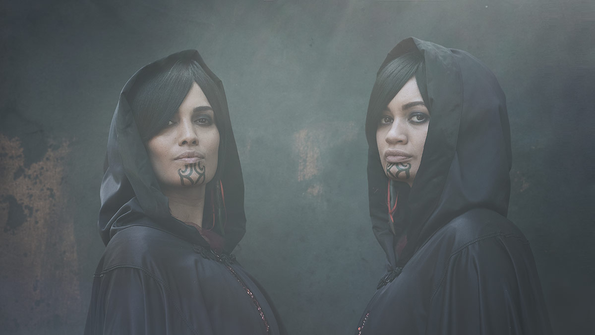 Two women in black cloaks with hoods and traditional black tattoos on their chins. Film still.